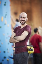 Smiling Hispanic man with arms crossed at outdoor climbing wall