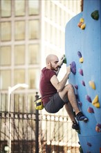 Hispanic man climbing outdoor climbing wall
