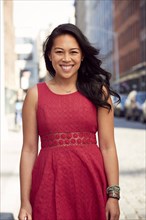 Pacific Islander woman smiling on city sidewalk