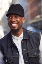Smiling African American man wearing hat and denim vest