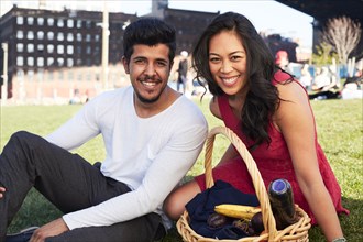 Couple sitting on grass with picnic basket