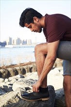 Middle Eastern man tying shoelace at waterfront