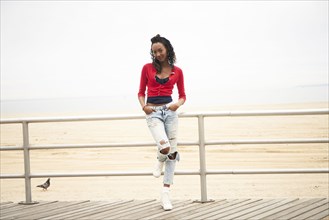 Black woman leaning on boardwalk railing