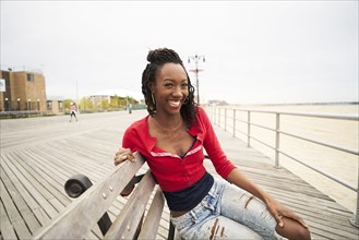 Black woman smiling on boardwalk bench