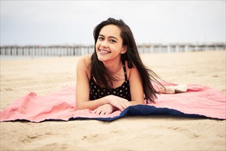 Mixed Race woman laying on blanket at beach