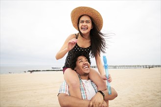 Man carrying woman on shoulders at beach