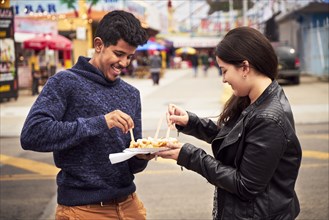 Couple sharing plate of food at amusement park