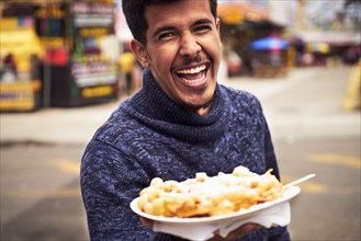 Laughing man showing plate of food at amusement park