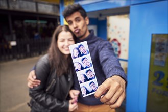 Couple showing photograph strip from photo booth