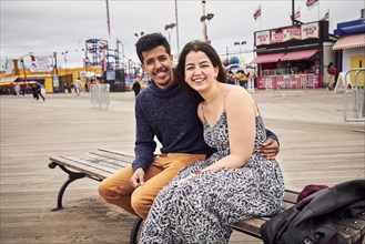 Couple sitting on boardwalk bench at amusement park
