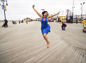 Woman smiling and jumping on boardwalk at amusement park