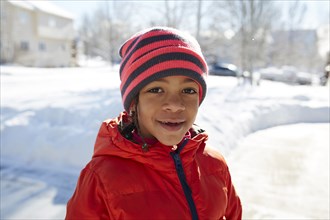 Smiling Mixed Race girl wearing hat and coat in winter