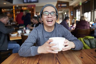 Laughing Asian man in coffee shop