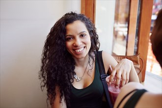 Smiling Black woman drinking smoothie in cafe