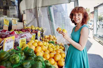 Hispanic woman shopping for lemons at fruit stand
