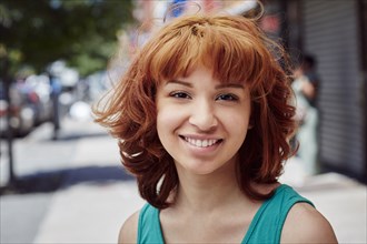 Hispanic woman smiling on city sidewalk
