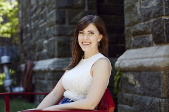 Smiling Caucasian woman sitting on chair outdoors