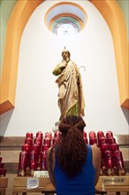 Kneeling woman praying to statue in church
