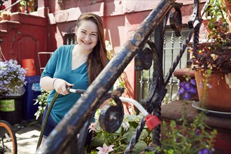Smiling Caucasian woman watering plants in garden