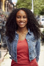 Smiling Mixed Race woman posing on city sidewalk