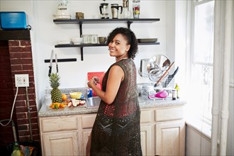 Smiling Mixed Race woman preparing fruit in kitchen