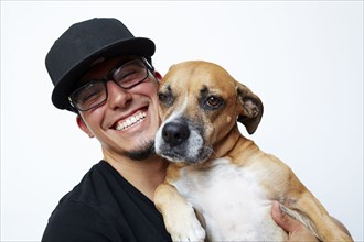 Smiling Hispanic man hugging dog