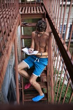 Caucasian man sitting on urban fire escape writing in journal