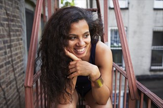Portrait of smiling woman relaxing on urban fire escape