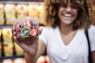 Black woman cup of fruit salad in grocery store