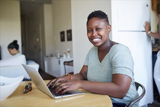 Smiling Black woman using laptop at table