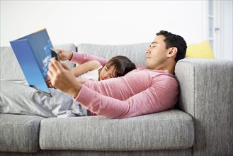 Father and daughter reading together on sofa