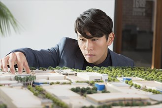 Korean businessman examining scale model