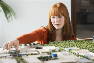 Caucasian businesswoman examining scale model