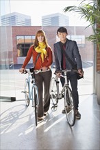 Business people wheeling bicycles in office