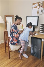 African American mother with daughter working from home