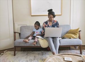 African American mother and daughter relaxing in living room