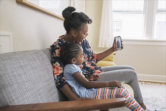 African American mother and daughter video chatting on cell phone