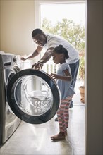African American father and daughter doing laundry