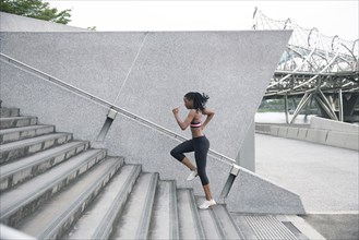 Mixed Race woman running up urban staircase