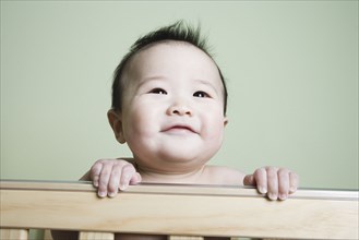 Asian baby smiling in crib