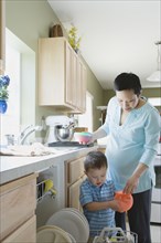 Mother and young son putting dishes in dishwasher