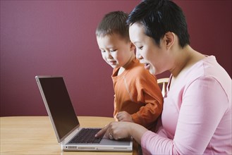 Asian mother and young son using laptop