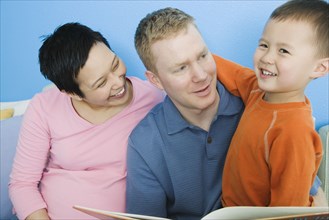 Pregnant parents reading to young son