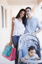 Young African couple with baby in stroller and shopping bags