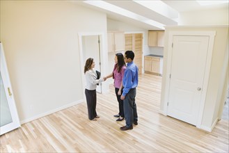 Asian couple shaking hands with real estate agent in new house