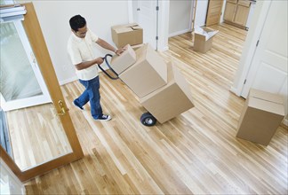 Asian man moving boxes in new house