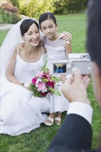Asian bride and flower girl having photograph taken