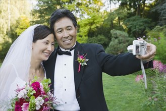 Asian newlyweds taking own photograph