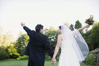 Asian newlyweds with arms raised