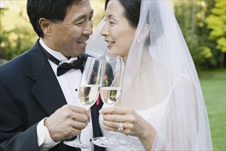 Asian newlyweds toasting with champagne